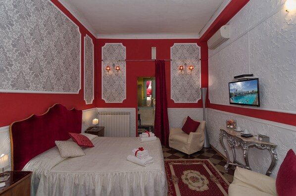 A hotel room with a bed, a TV, a chair, and a table. - La Mimosa Bed and Breakfast (Lucca)