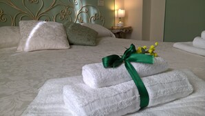 A neatly made bed with white towels and a green ribbon, a metal headboard, and a bedside table with a lamp. - La Mimosa Bed and Breakfast (Lucca)