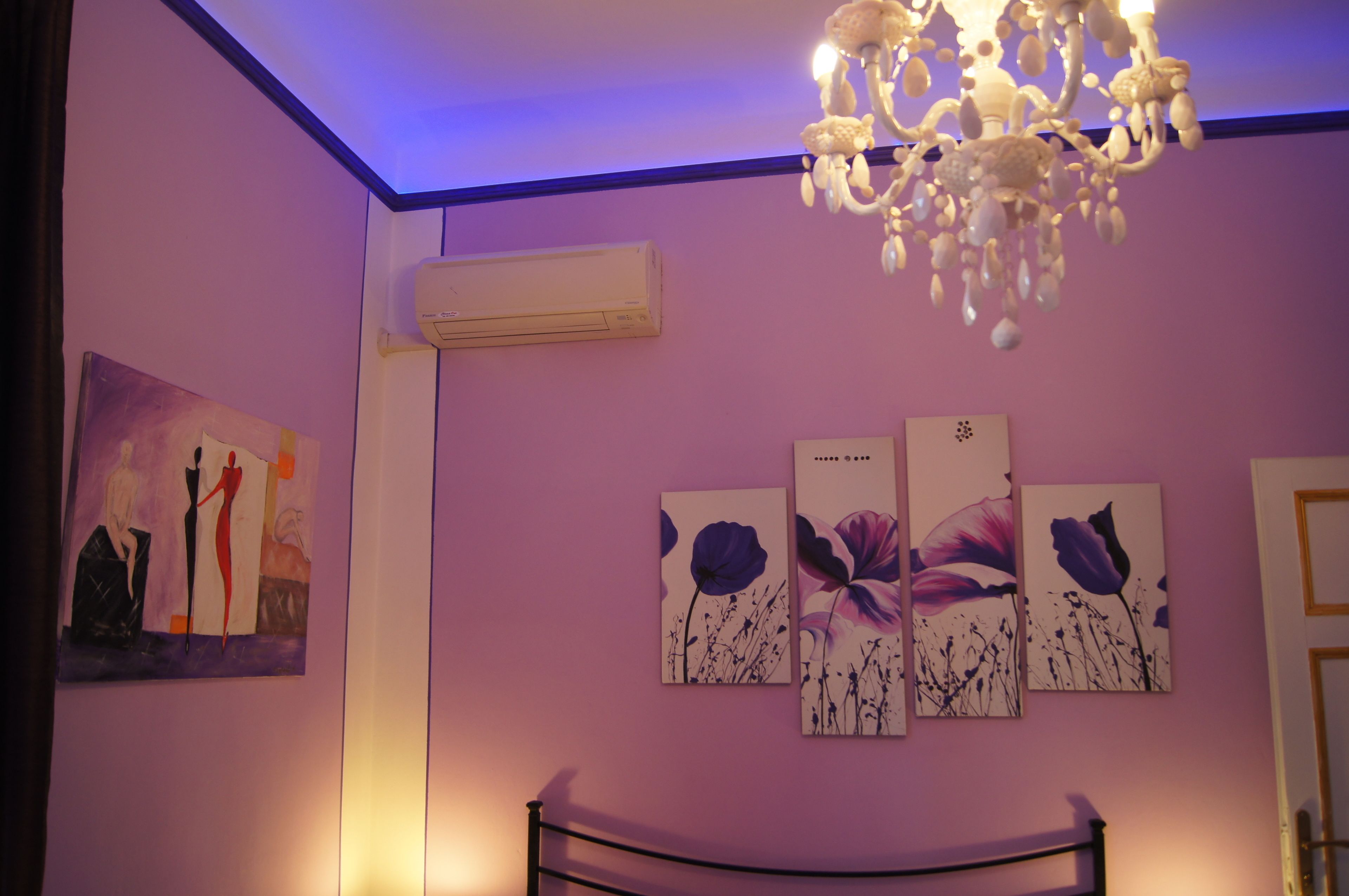 A bedroom with a bed, a chandelier, and wall art.