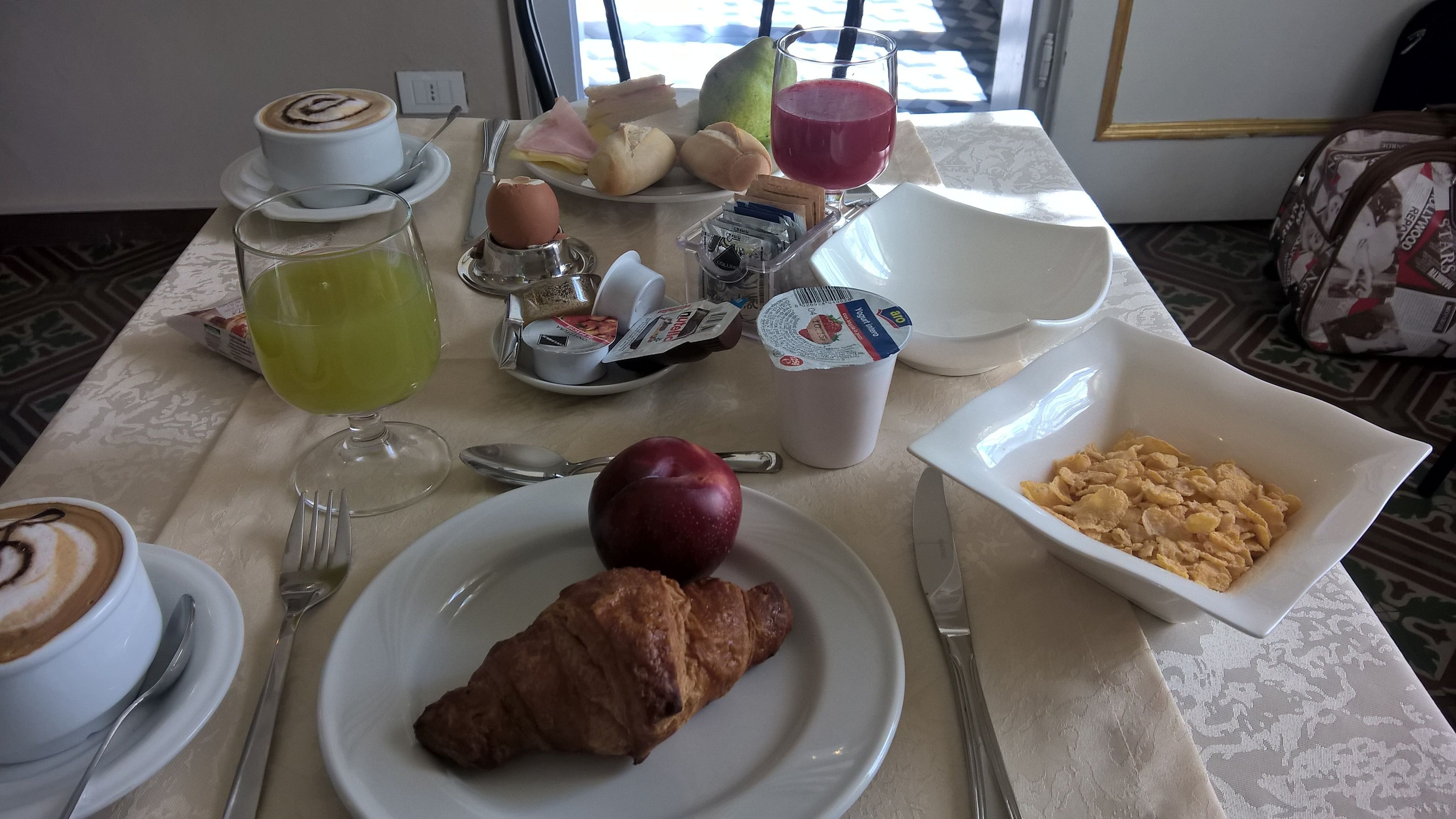 Une table de petit-déjeuner avec un croissant, une pomme et un bol de céréales.