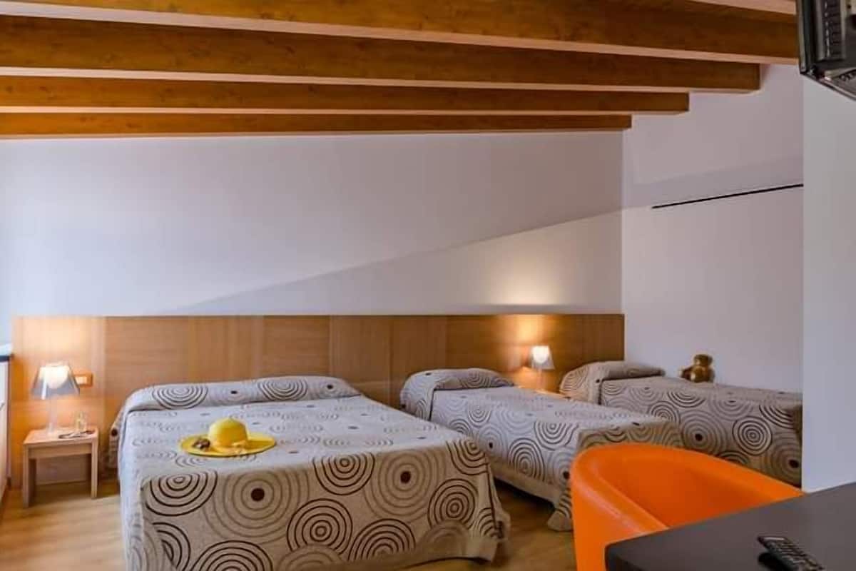A hotel room with two beds, a small table, a chair, and a desk.