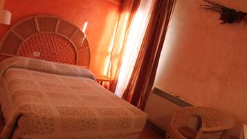 A room with a bed, a chair, a lamp, and a wall-mounted air conditioner.