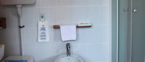Un baño con inodoro, bidé y cabina de ducha de vidrio.