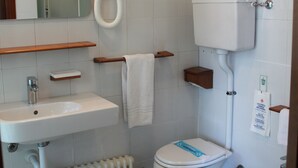 A bathroom with a white sink, two toilets, a bidet, a mirror, and a towel rack. - Le Pageot (Aosta)