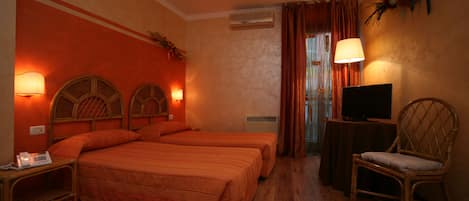 A hotel room with two beds, a television, a chair, and a desk with a lamp.