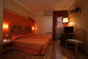Una habitación de hotel con dos camas, televisión, una silla y un escritorio con lámpara.
