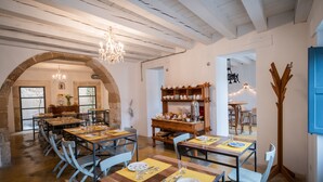Un comedor con varias mesas dispuestas para los comensales, una araña de cristal y un rústico arco de piedra.