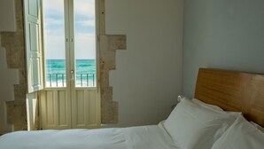 Un dormitorio con cama, cabecera de madera y vista al océano a través de una puerta.