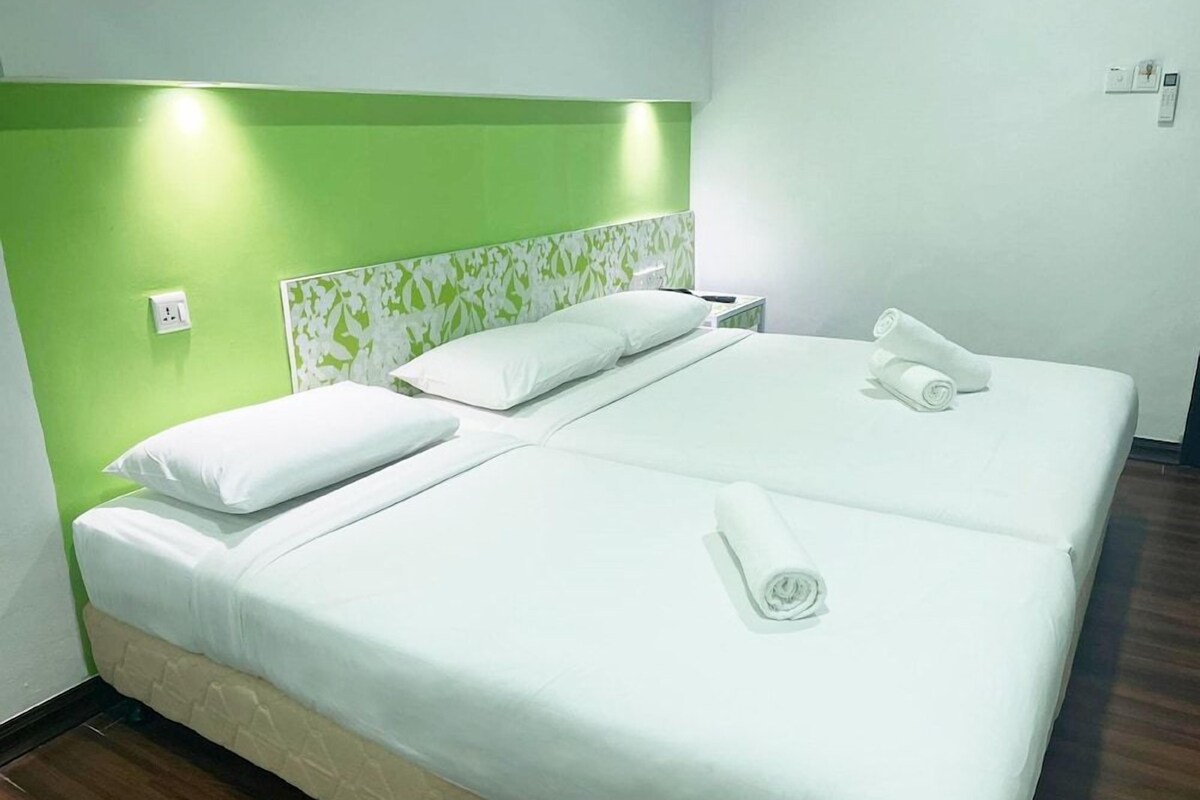 A hotel room with a bed, a nightstand, and a green wall.