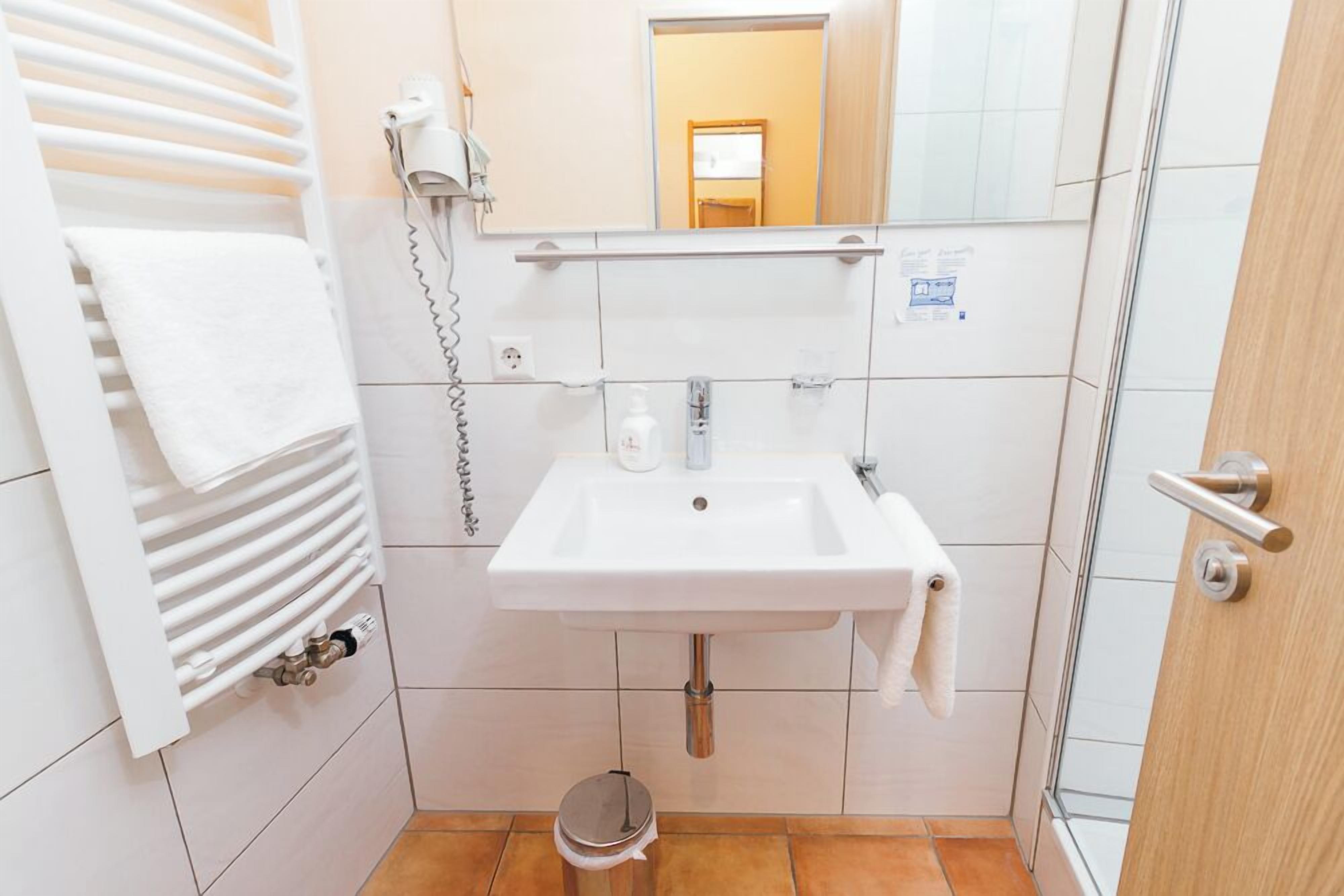 A bathroom with a white sink, towel rack, and a mirror.