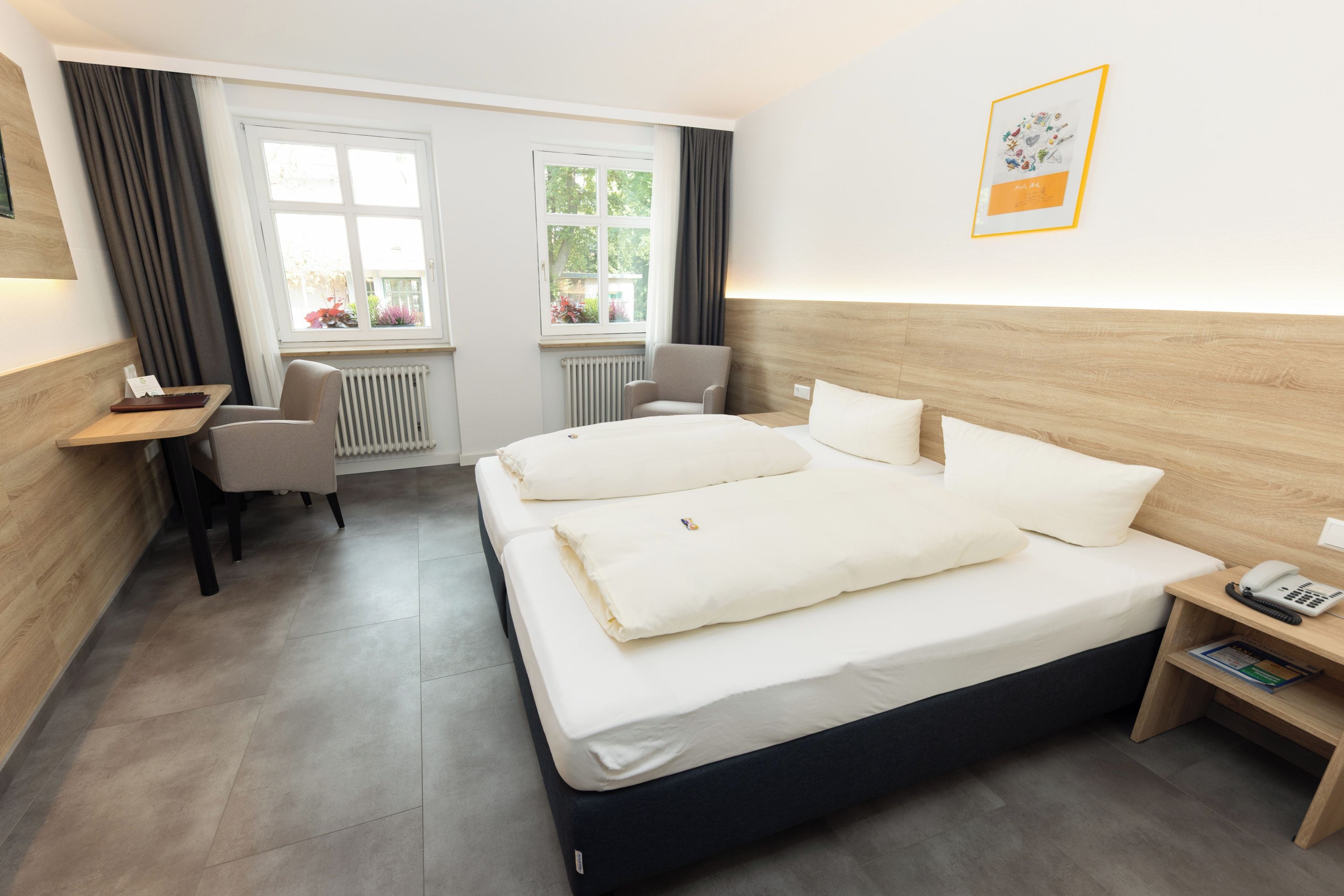 Una habitación de hotel con cama, mesita de noche, silla y escritorio.