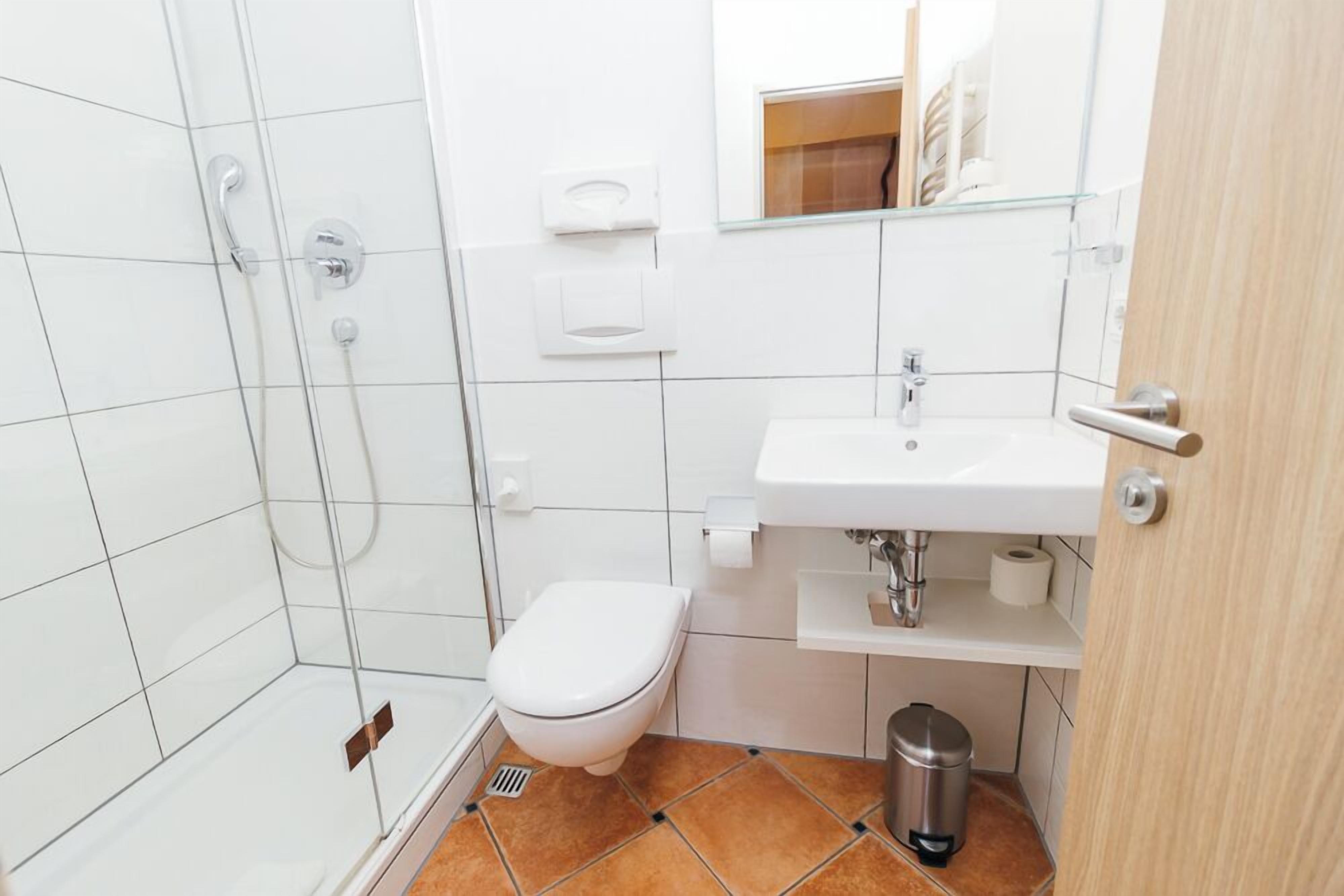 Une petite salle de bain avec une douche, des toilettes, un lavabo et un miroir.