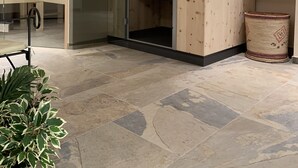 A modern bathroom with a wooden cabinet, a glass shower enclosure, and a tiled floor. - Hotel Garni Brugger (Lindau)
