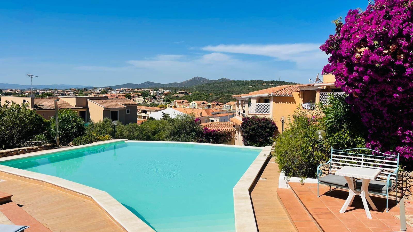 A swimming pool with a view of a residential area and mountains in the background.