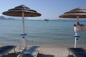 Ranta lähistöllä, valkoista hiekkaa, aurinkotuoleja, aurinkovarjoja