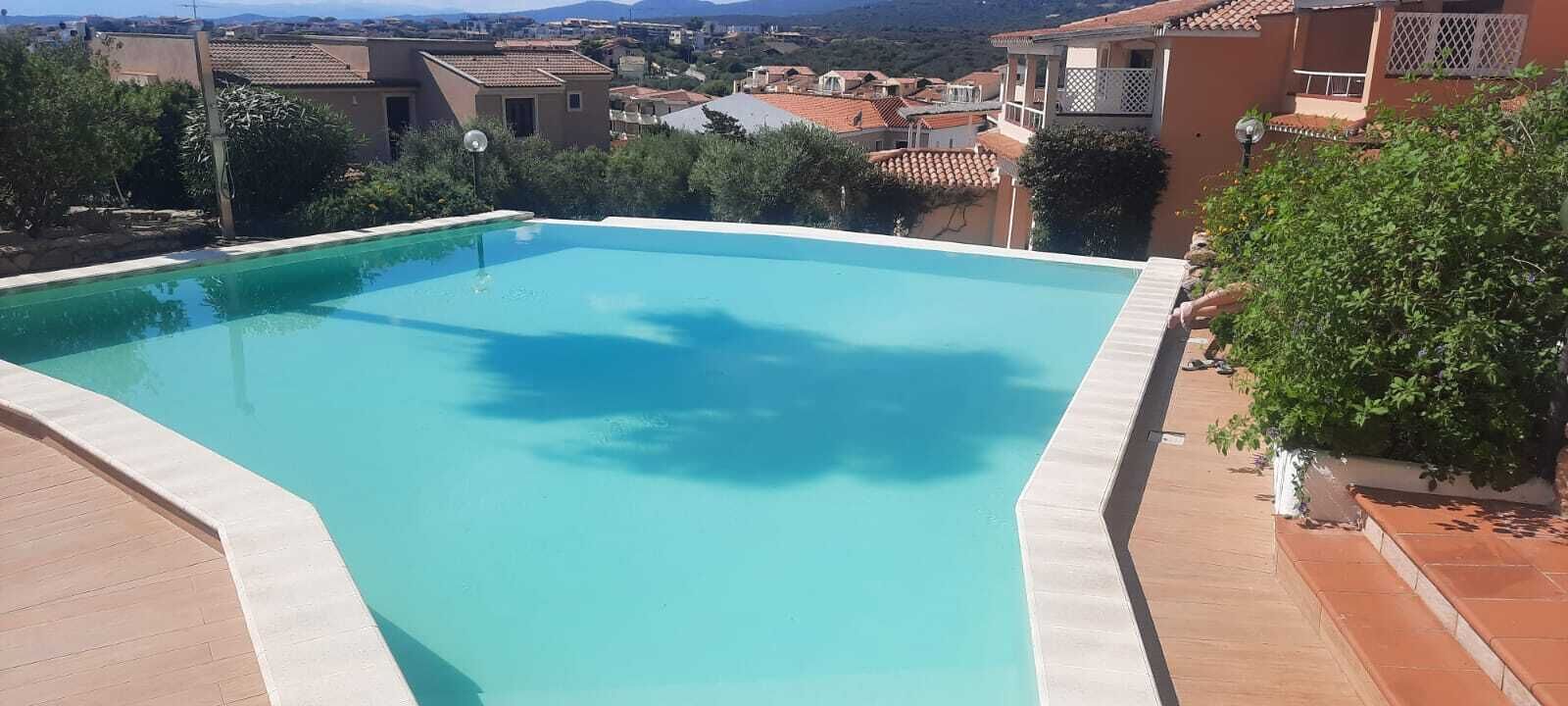 Una piscina rectangular con superficie de agua azul cristalina, rodeada por una solana con baldosas.