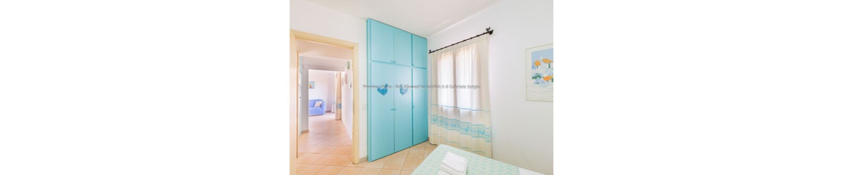 A room with a bed, a wardrobe, and a window with curtains.