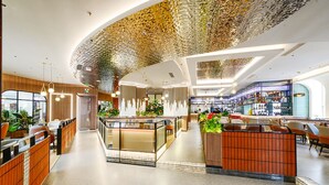 A modern hotel lobby with a curved ceiling, seating areas, and a bar. - Bayshore Hotel Dalian (Dalian)