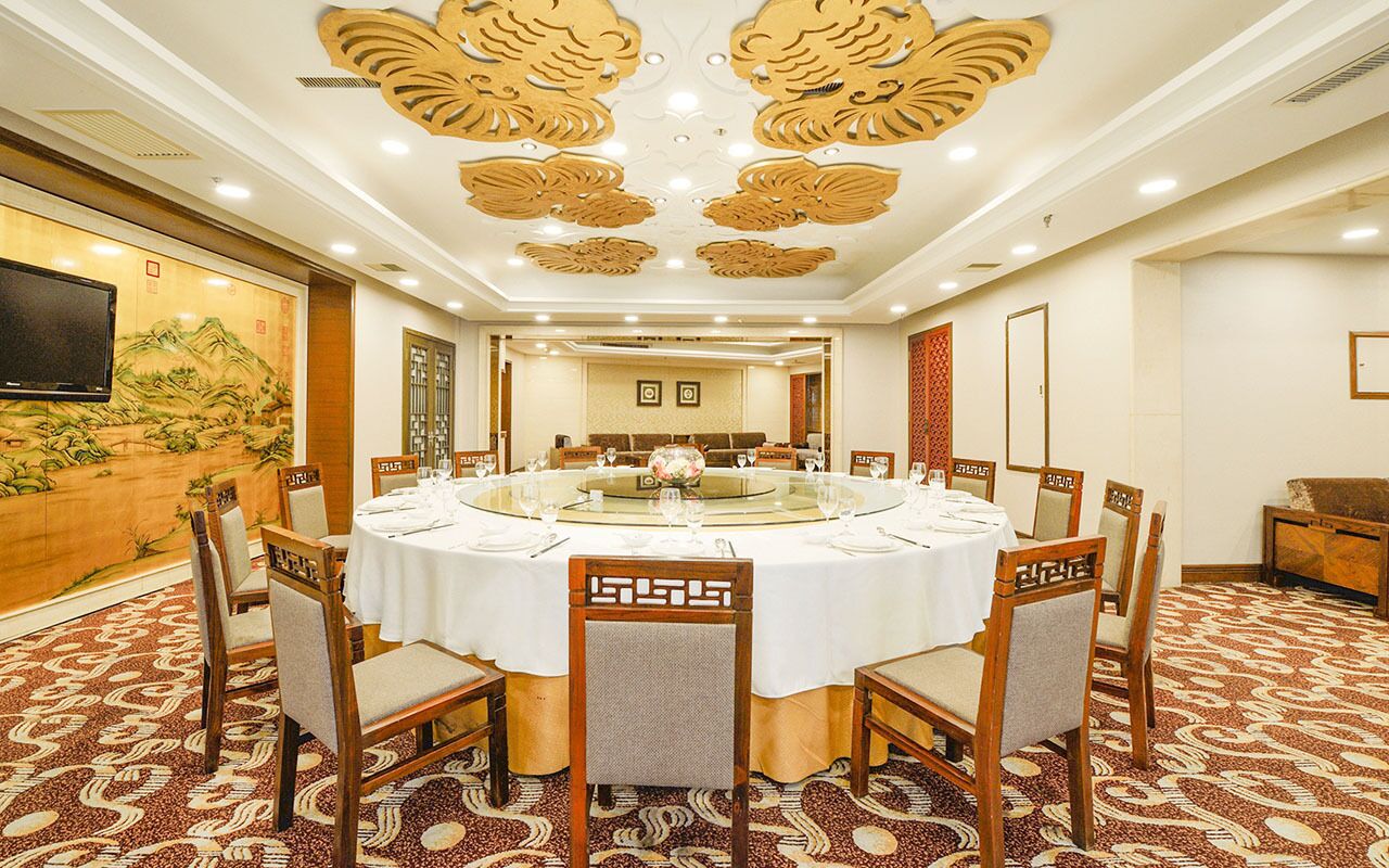 A conference room with a round table, chairs, and a television on the wall.