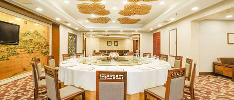 A conference room with a round table, chairs, and a television on the wall.