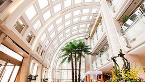 A spacious atrium with a high ceiling, large windows, and a central palm tree. - Bayshore Hotel Dalian (Dalian)