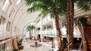 A spacious atrium with high ceilings, palm trees, and a central seating area. - Bayshore Hotel Dalian (Dalian)