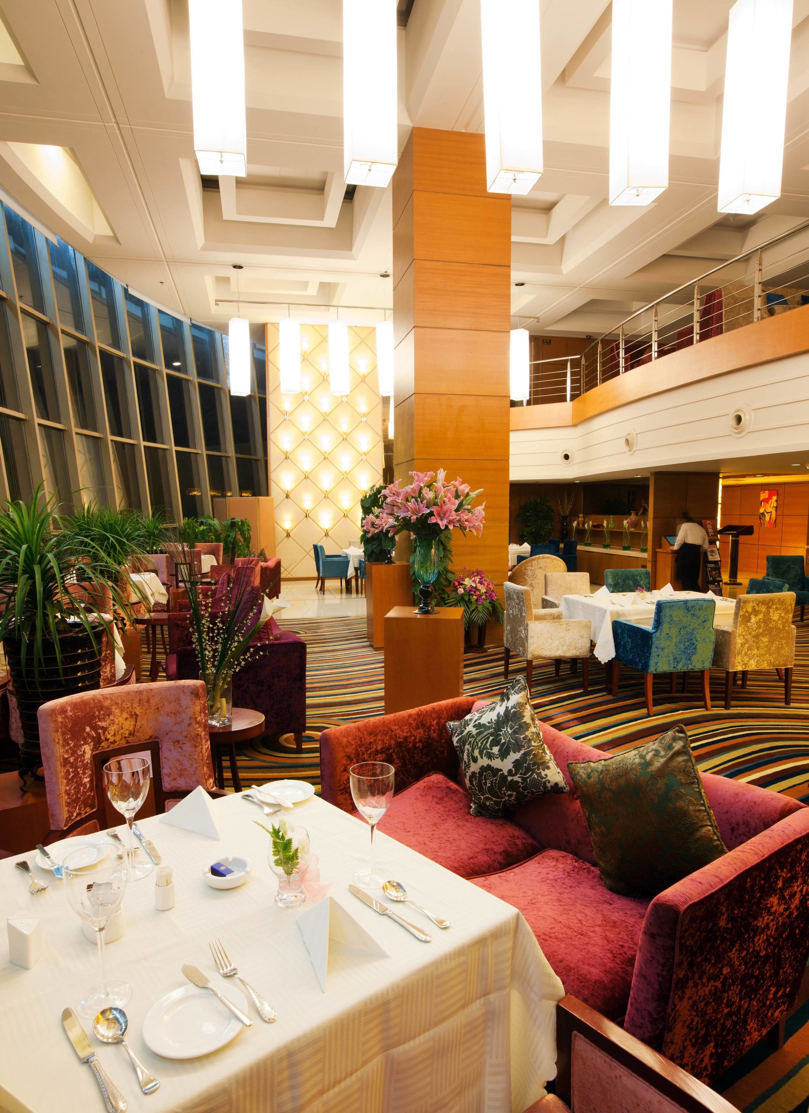 Eine Hotlellobby mit Essbereich, Sitzgelegenheiten und einer Treppe.