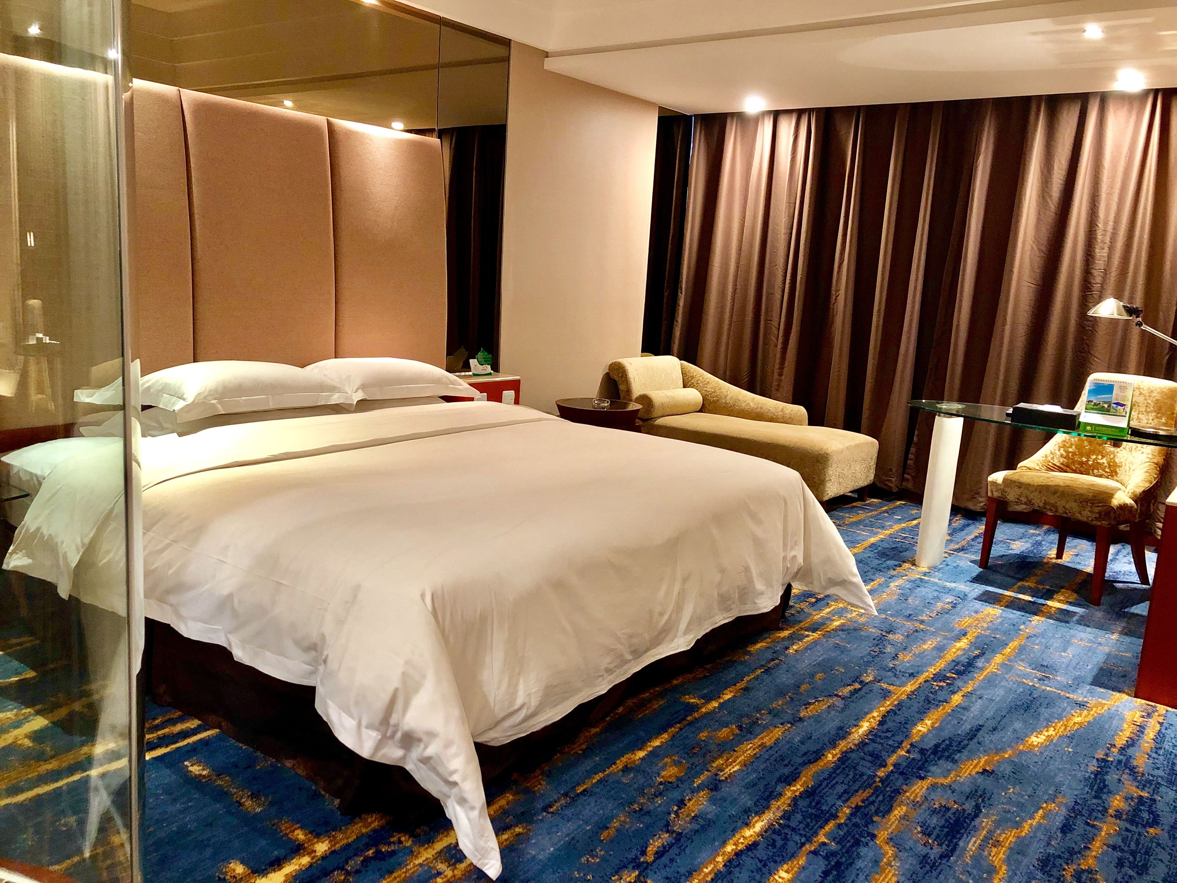 A hotel room with a large bed, a sofa, a desk, and a chair.
