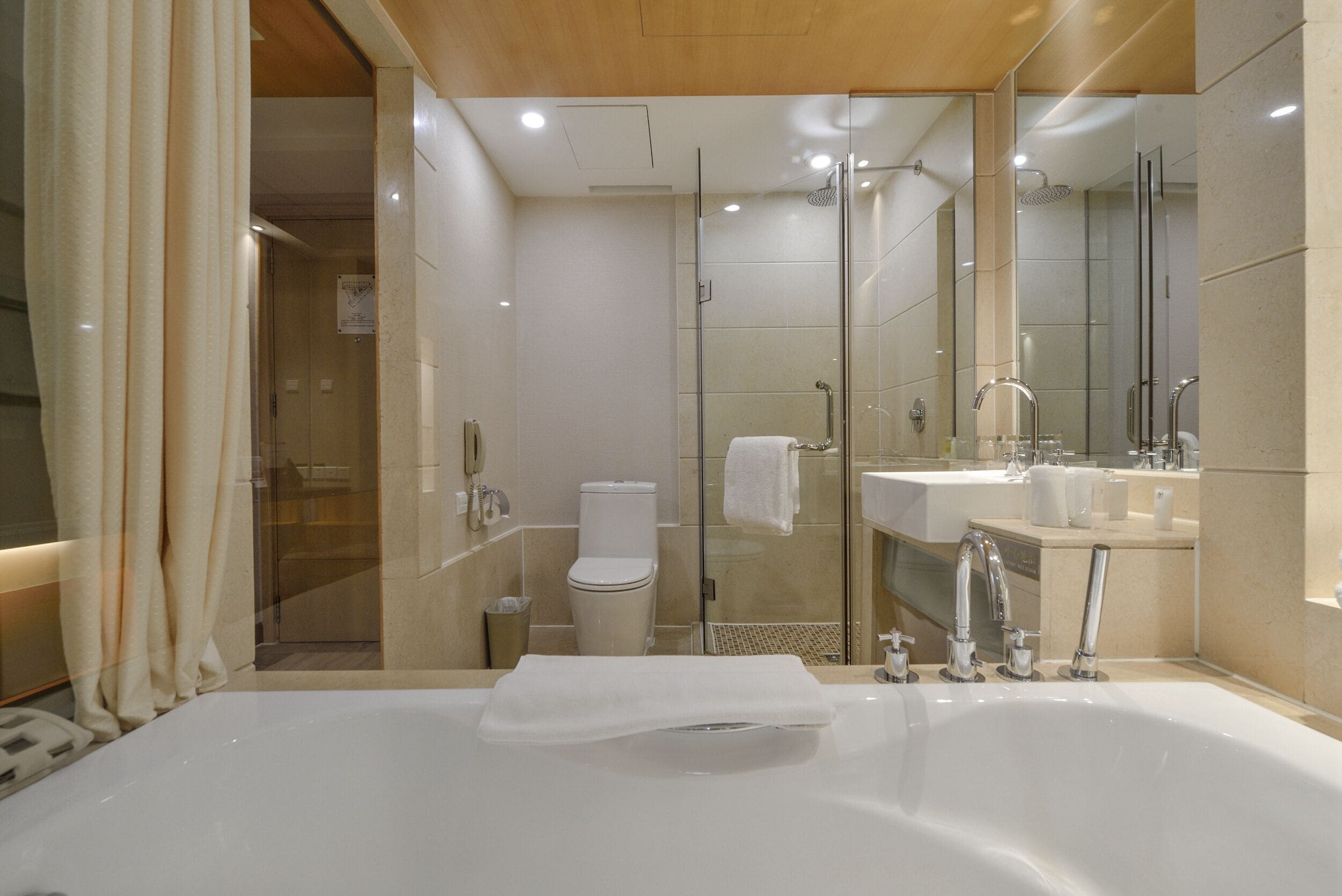 Un baño moderno con una bañera grande, una ducha con mampara de cristal y un inodoro separado.