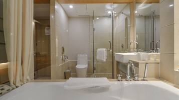 Un baño moderno con una bañera grande, una ducha con mampara de cristal y un inodoro separado.