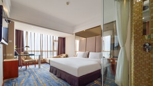 A hotel room with a large bed, a desk with a chair, a TV, and a bathroom with a shower and a mirror. - Bayshore Hotel Dalian (Dalian)