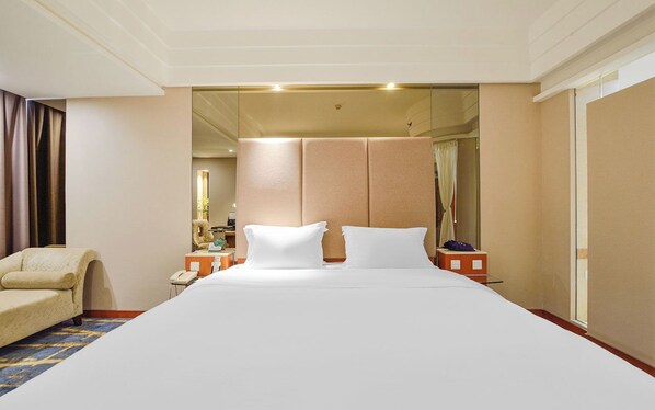 A hotel room with a large bed, a chair, a nightstand, and a mirror. - Bayshore Hotel Dalian (Dalian)