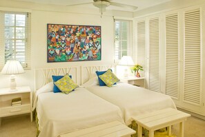 A bedroom with two beds, a large painting on the wall, and white furniture.