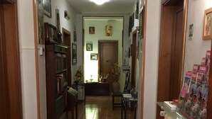 A hallway with a tiled floor, wooden doors, and a reception desk with magazines. - Soggiorno Petrarca (Florence)