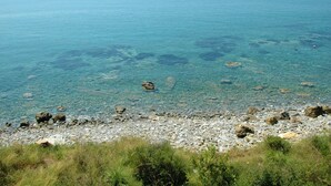 A rocky shoreline with clear blue water and distant horizon.