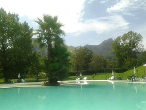 Una piscina al aire libre, sillones reclinables de piscina