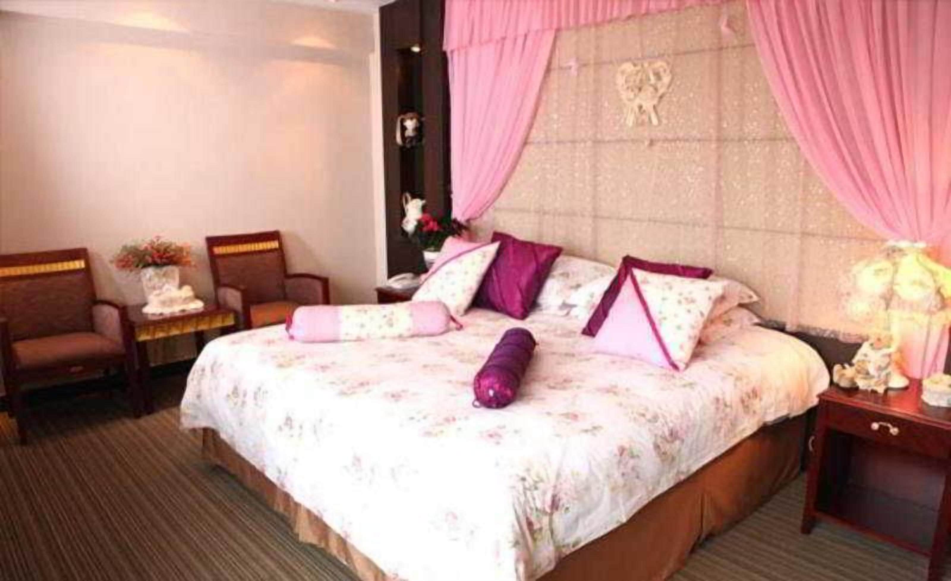 Ein Hotelzimmer mit einem Bett, zwei Stühlen, einem Nachttisch und einer Lampe.