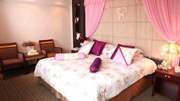 Ein Hotelzimmer mit einem Bett, zwei Stühlen, einem Nachttisch und einer Lampe.