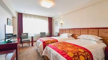Een hotelkamer met twee bedden, een bureau, een stoel, een televisie en een raam met gordijnen.