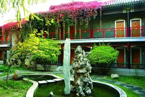 Un bâtiment traditionnel doté d’une cour intérieure, d’une formation rocheuse et d’un élément décoratif aquatique.