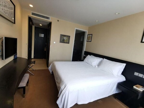 A hotel room with a bed, bedside table, and a TV.
