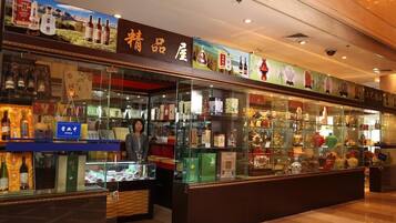 Una tienda con vitrinas repletas de diversos artículos, un letrero con caracteres chinos y una persona dentro.