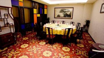 Un salón de conferencias con una mesa redonda, sillas y una alfombra estampada.