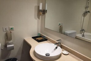 Une salle de bain avec un lavabo blanc, un miroir, des toilettes et une douche.