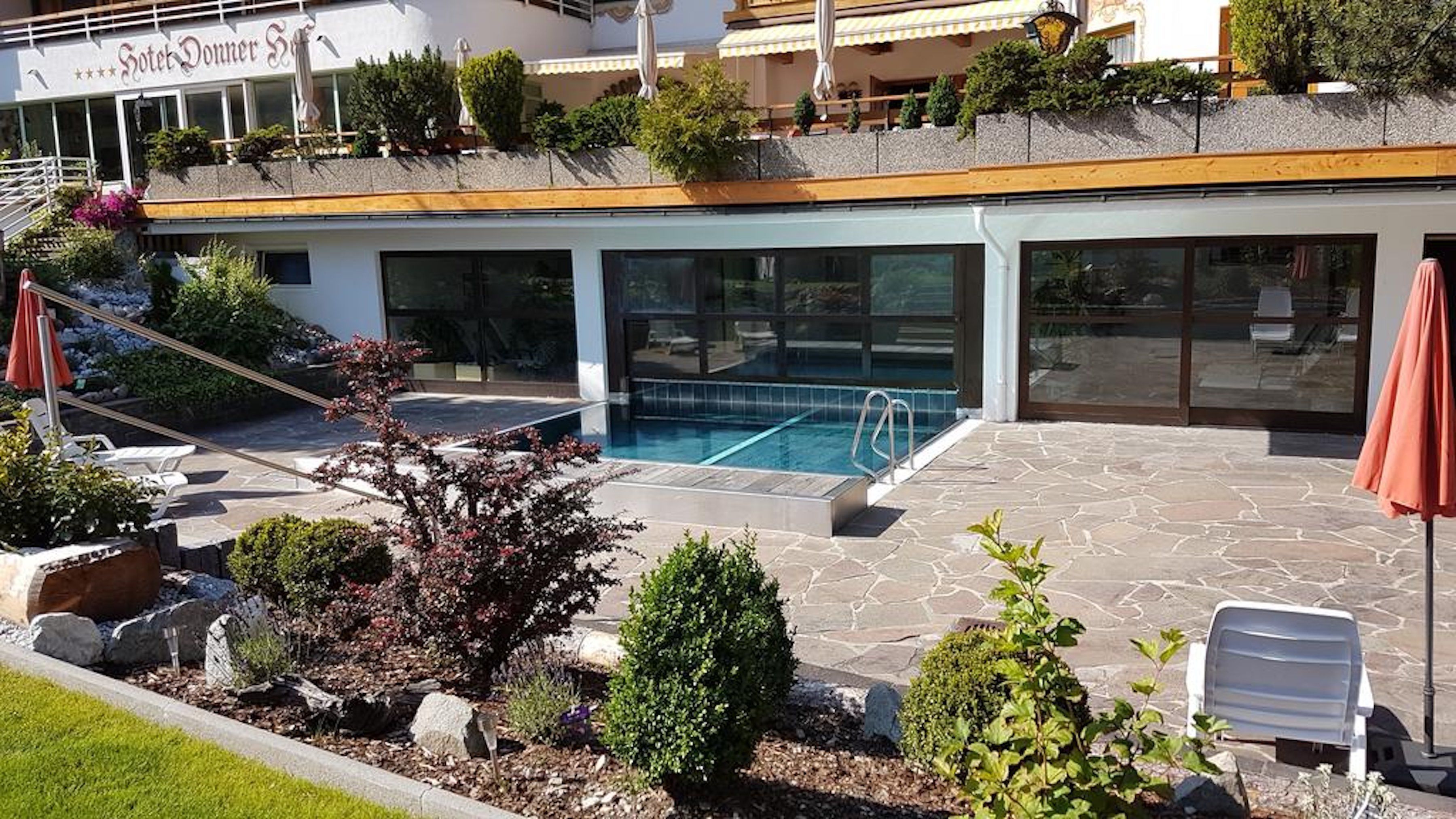 A hotel with a swimming pool, outdoor seating, and a garden area.