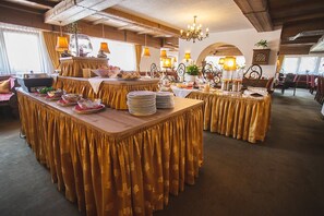 A dining area with round tables covered in gold tablecloths, equipped with plates, glasses, and cutlery. - Hotel Donnerhof (Fulpmes)
