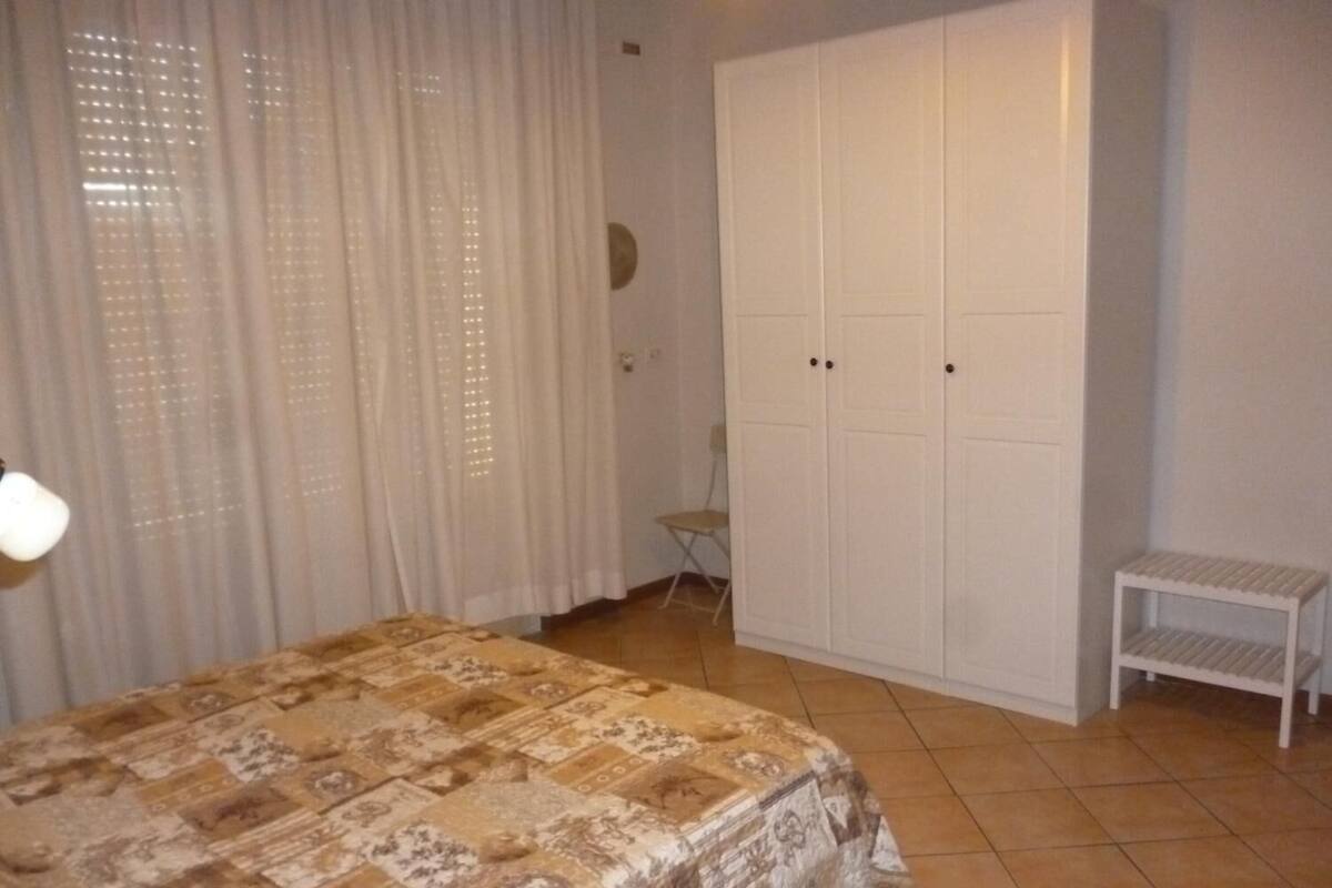 A bedroom with a bed, a wardrobe, a small table, and a chair.