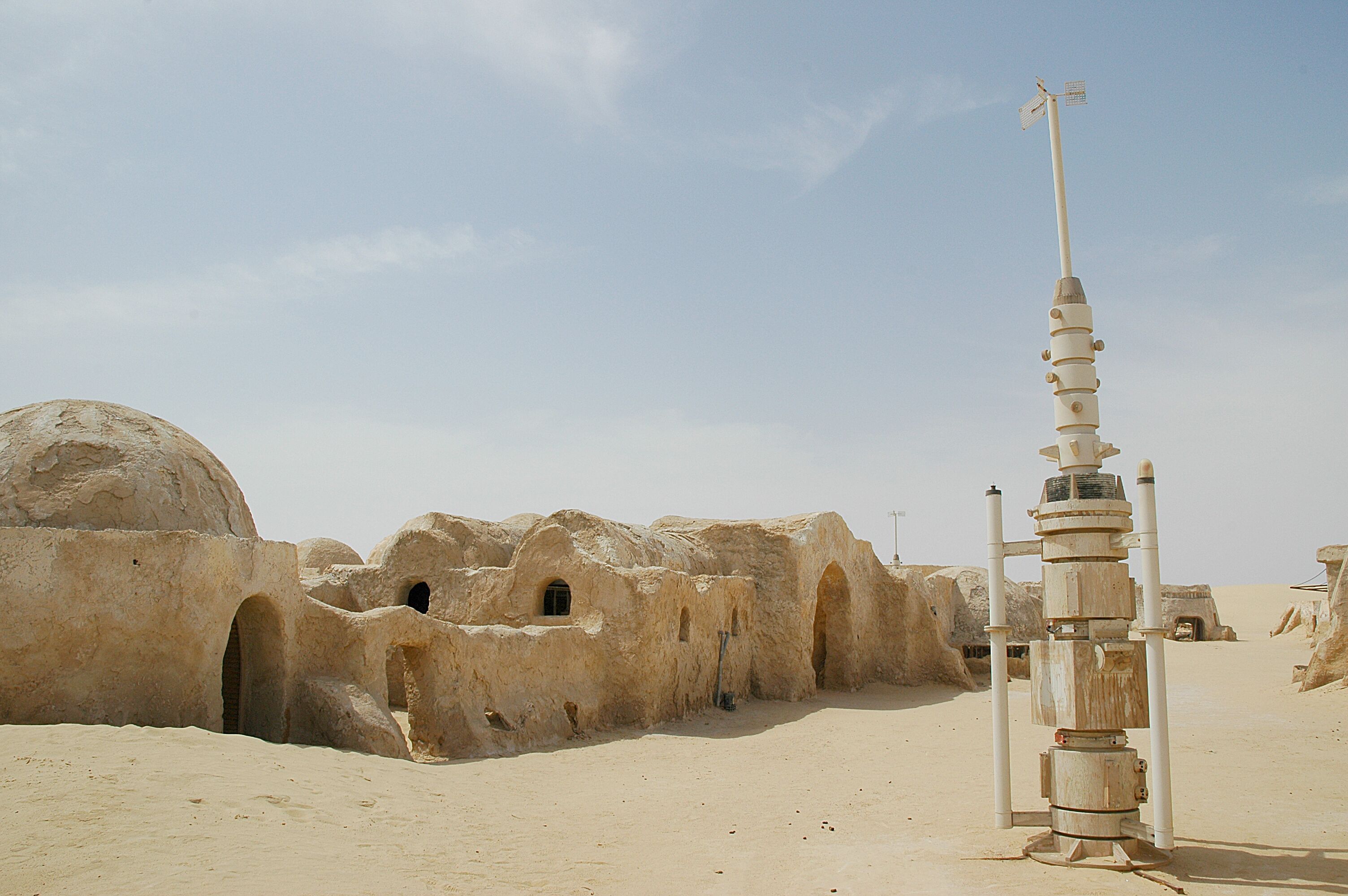 A desert landscape with ancient, rounded stone structures and a tall, narrow tower.