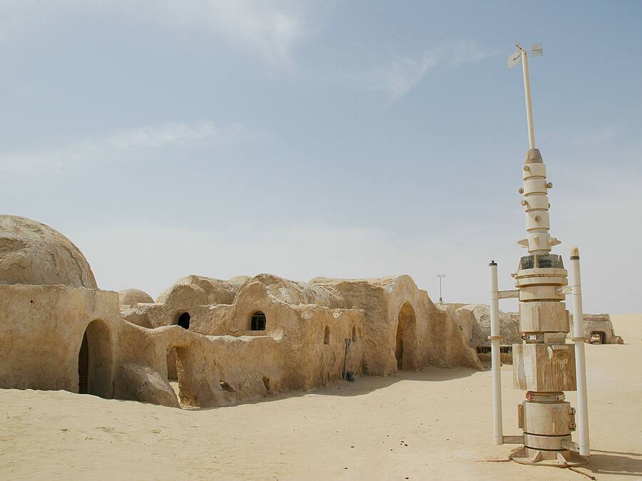 A desert landscape with ancient, rounded stone structures and a tall, narrow tower.