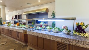 A buffet with various food items and decorative flowers. - El Mouradi Tozeur (Tozeur)